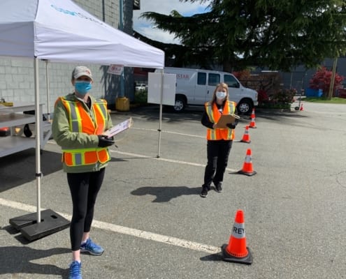 Two women volunteer staff standing with lists in Greater Vancouver, BC
