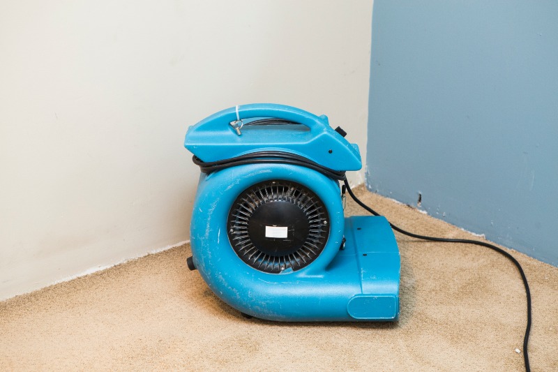 Water damaged walls and floors in house. Dehumidifier pointing at walls.